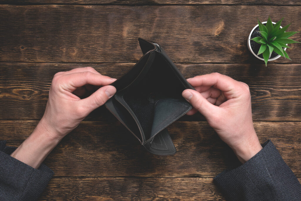 Empty wallet in hands on an office table background. No money concept. Debts. Bankruptcy.