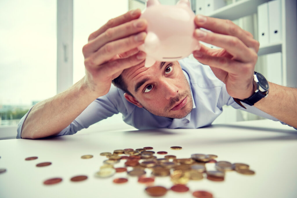businessman shaking piggy bank and getting coins at office