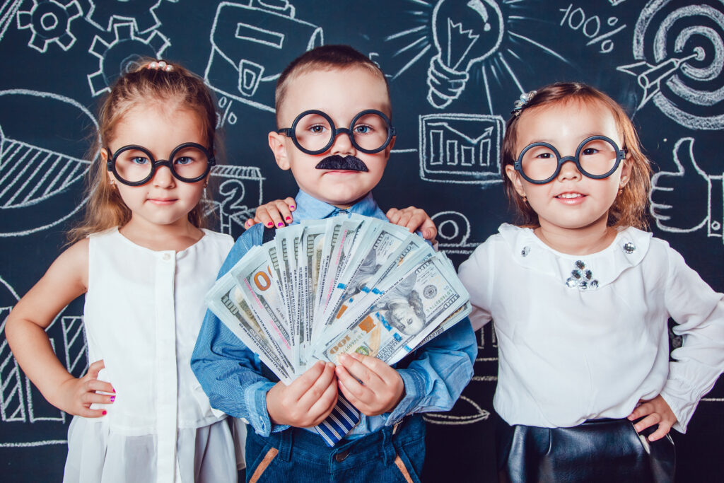 Little boy in glasses and mustache on dark background with a pattern. He holds banknotes in hand. Two girls standing the sides