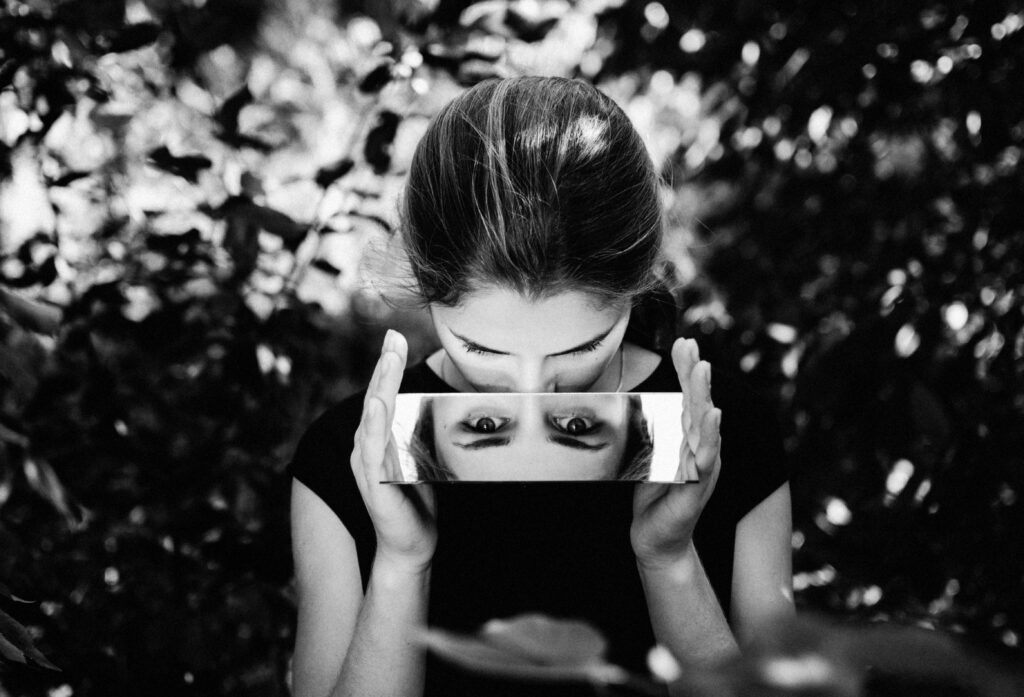 black and white photo of woman looking in mirror showing her eyes