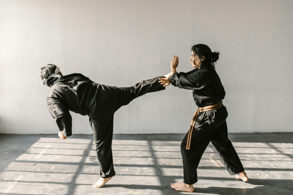 two people practicing self-defense, one is blocking the other's kick