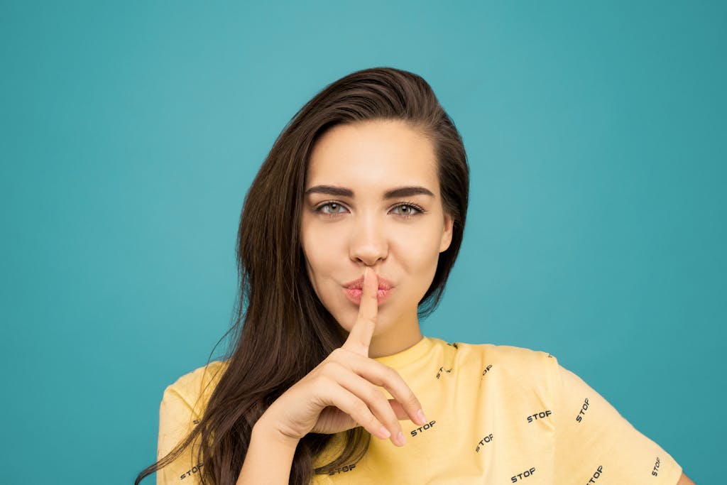 woman in yellow shirt holding finger to mouth