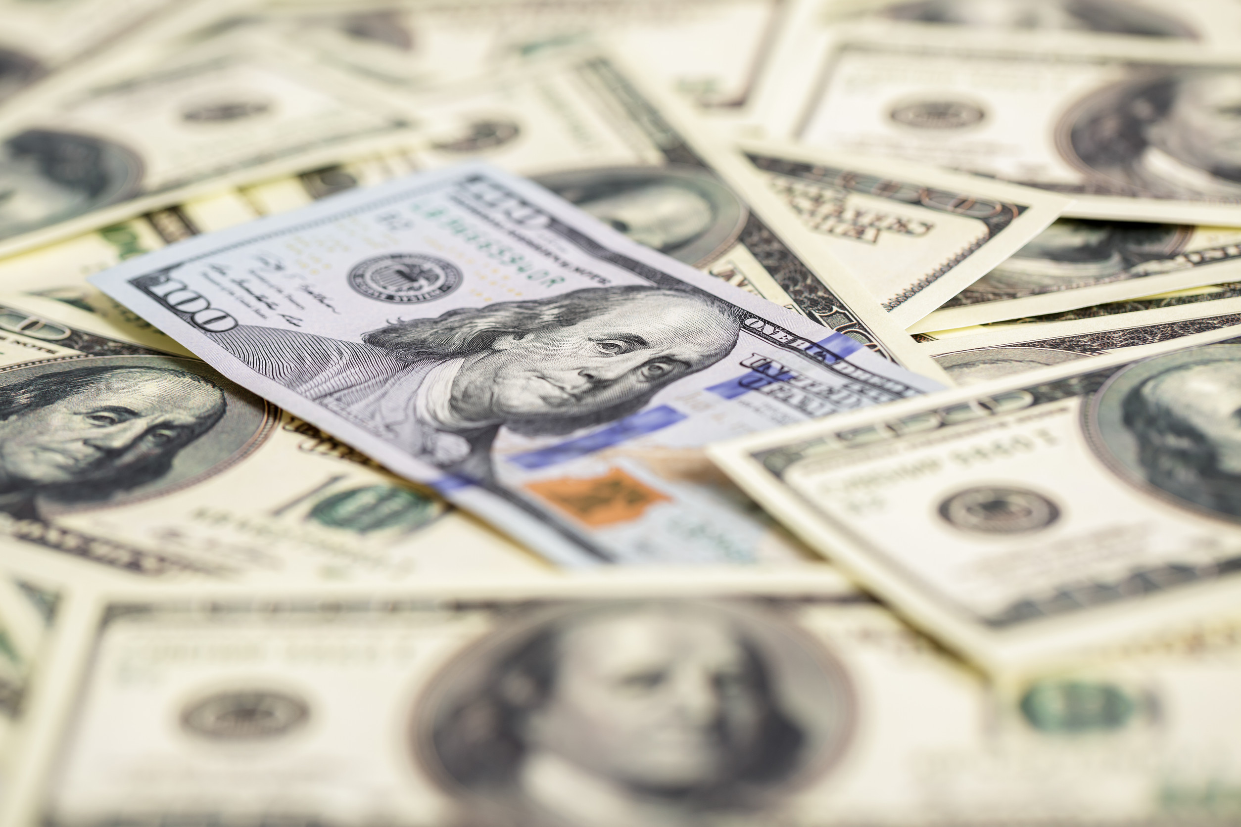 close up view of cash money. one new and pile of old bills hundred dollar bills.