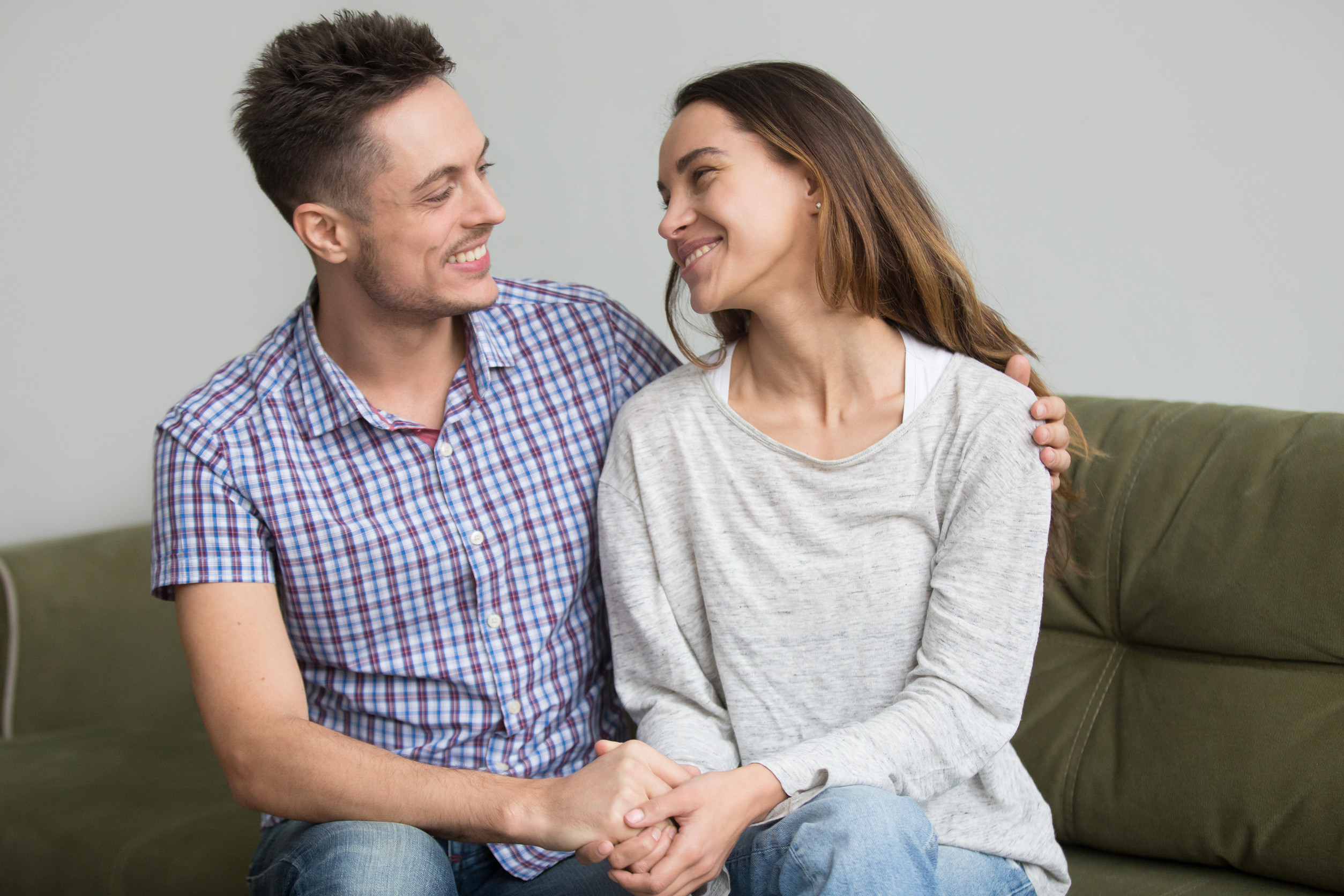 Happy smiling couple embracing and holding hands looking in each other eyes, reconciled after argument or quarrel. Husband hugging wife showing support and bright future in relationships.