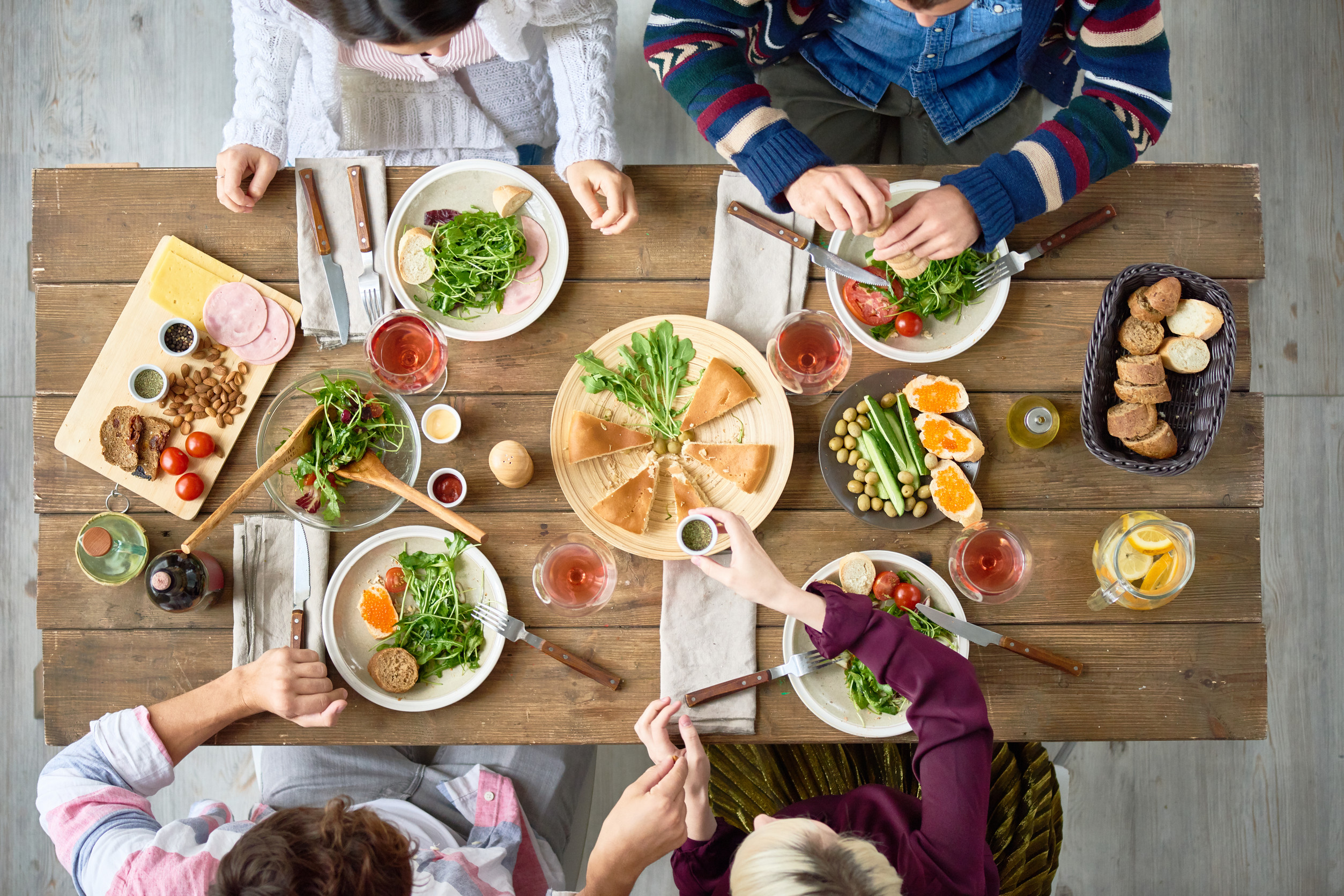 Top view of four people eating delicious food at festive dinner table in cafe or restaurant celebrating holiday