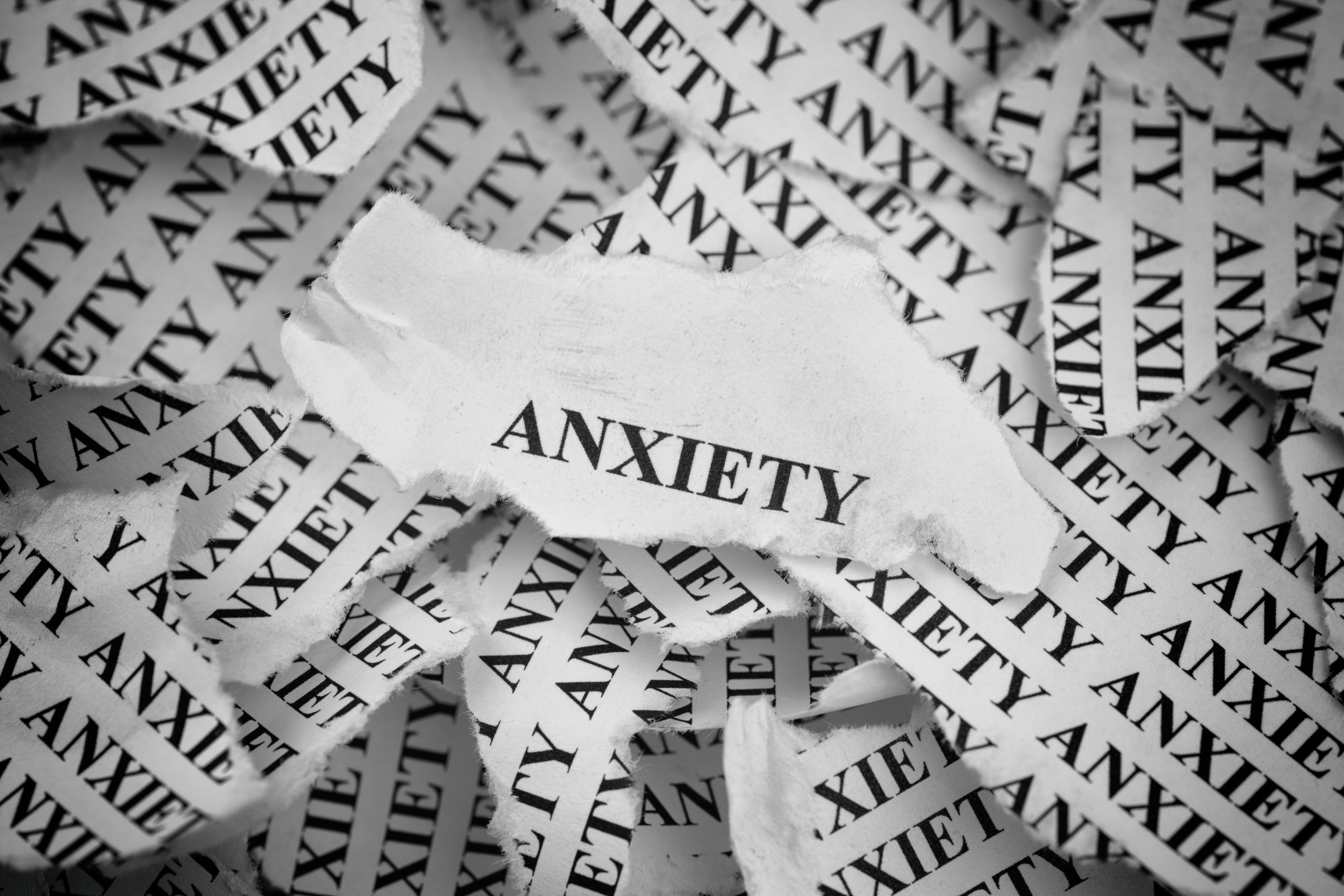Torn pieces of paper with the word "Anxiety". Concept Image. Black and White. Close-up.