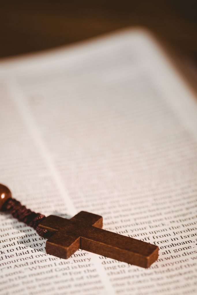 Wooden cross of rosary beads on open bible