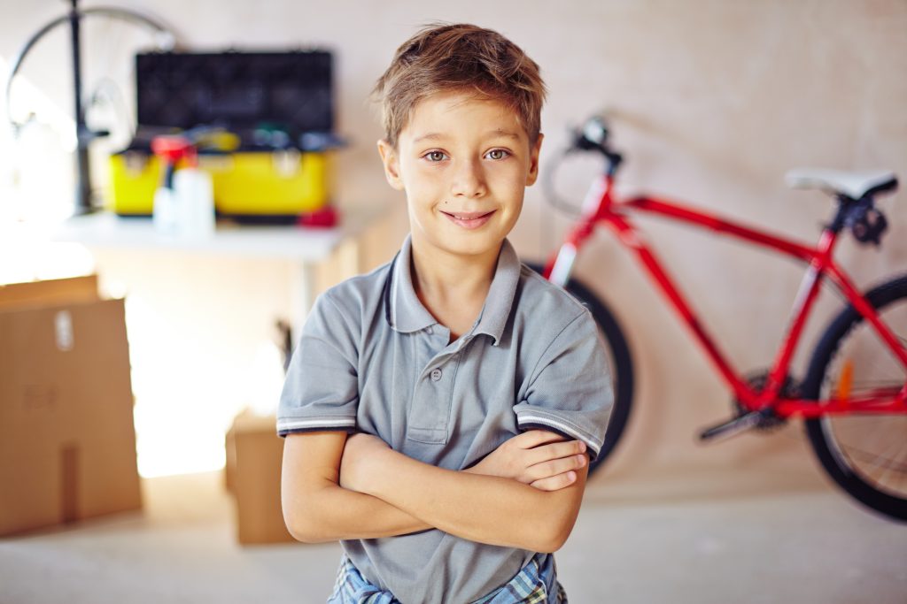 Little boy with crossed arms looking at camera in garage
