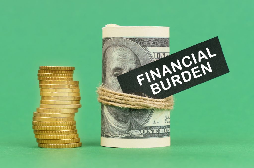 Business concept. On a green surface are coins and dollars in a bundle. On the dollar sign with the inscription - Financial burden