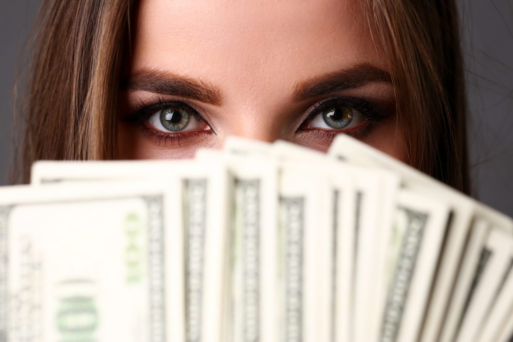 Beautiful european woman portrait. Scattering money notes dollars in fashion vows style mulatto curly hair with white locks eye view of the camera