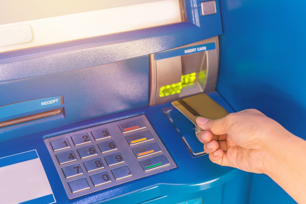 Hand insert credit card to ATM bank cash machine for withdraw money.