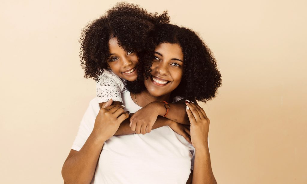afro american mother and daughter smiling happy hugging over isolated background.