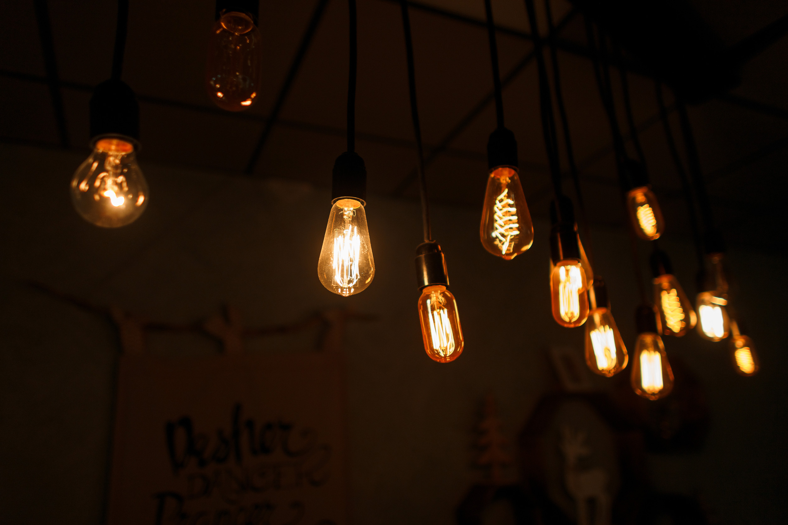 A group of vintage orange bright incandescent bulbs hang in a bar against the background of a vintage wall. Electric glare