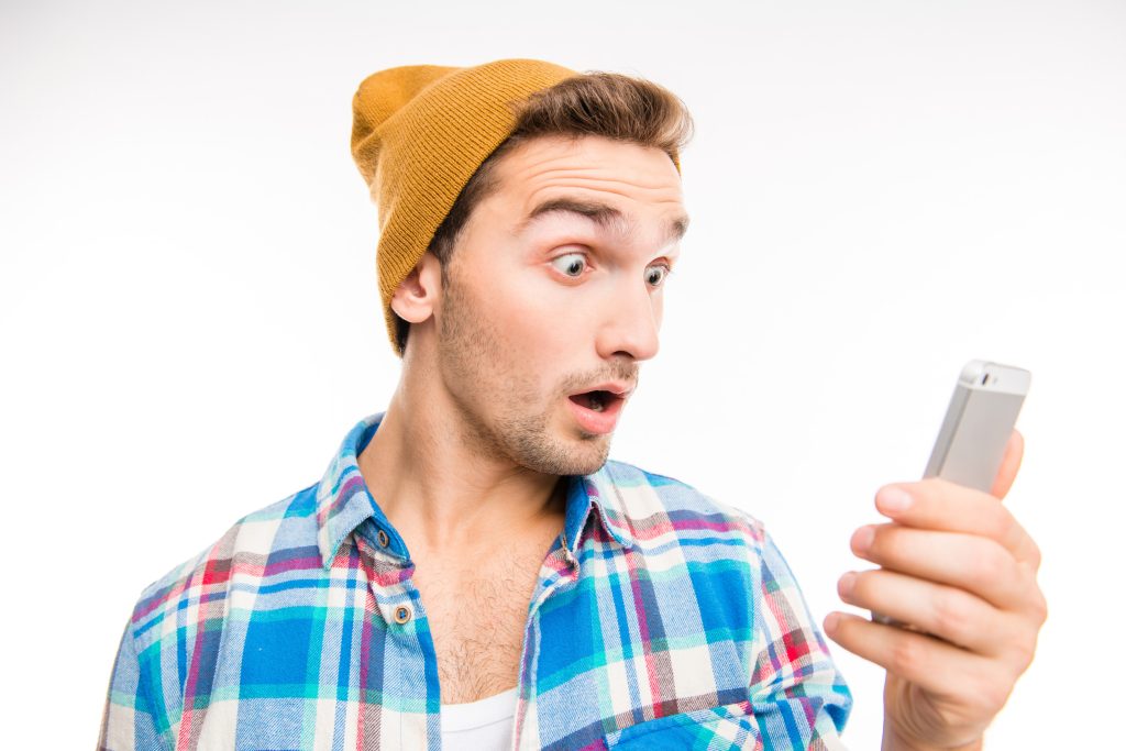 Handsome surprised man with hat holding the phone