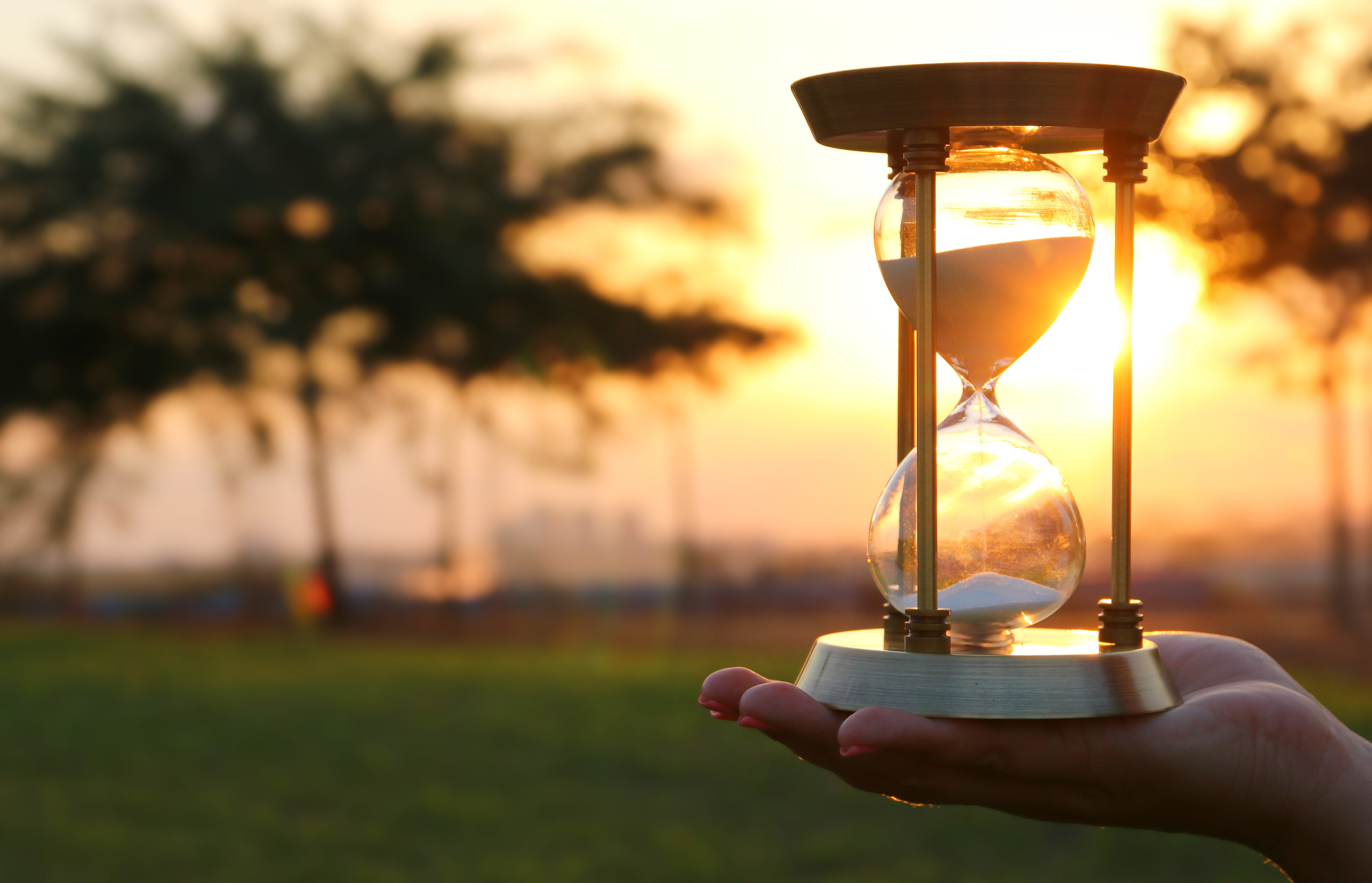Young woman holding Hourglass during sunset. vintage style