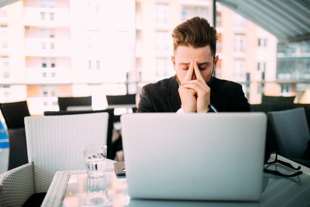business man woking at laptop with head ache in cafe shop at terrace.