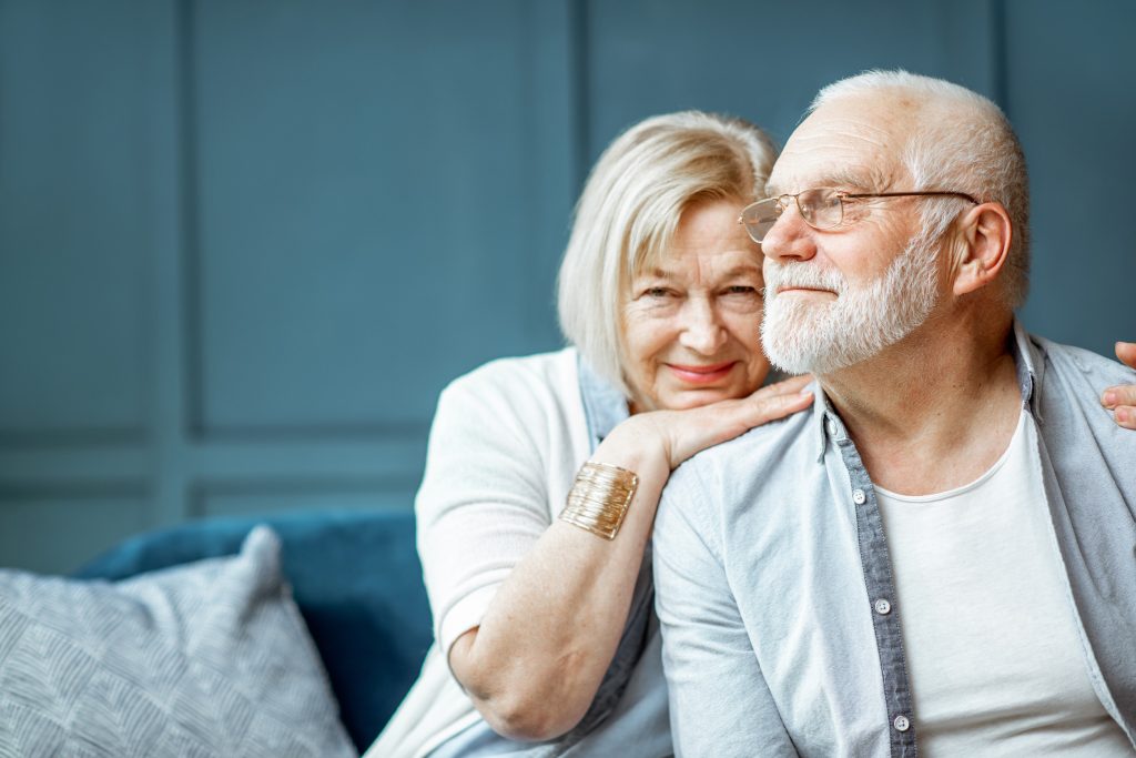 Portrait of a beautiful senior couple embracing each other, sitting on the couch at home