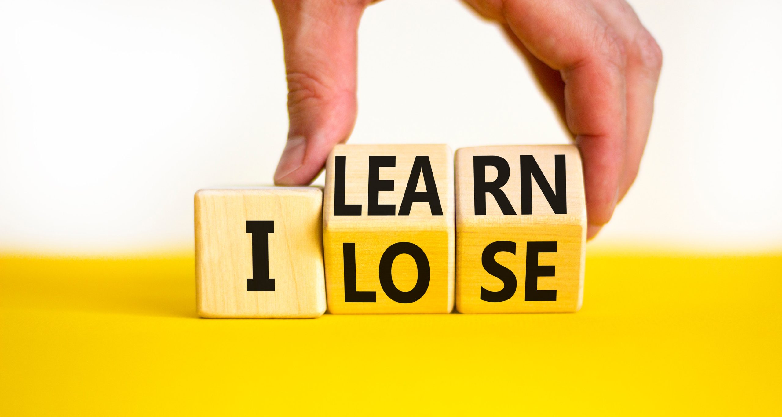 I learn or lose symbol. Concept words I learn and I lose on wooden cubes. Businessman hand. Beautiful yellow table white background. Business and i learn or lose concept. Copy space.