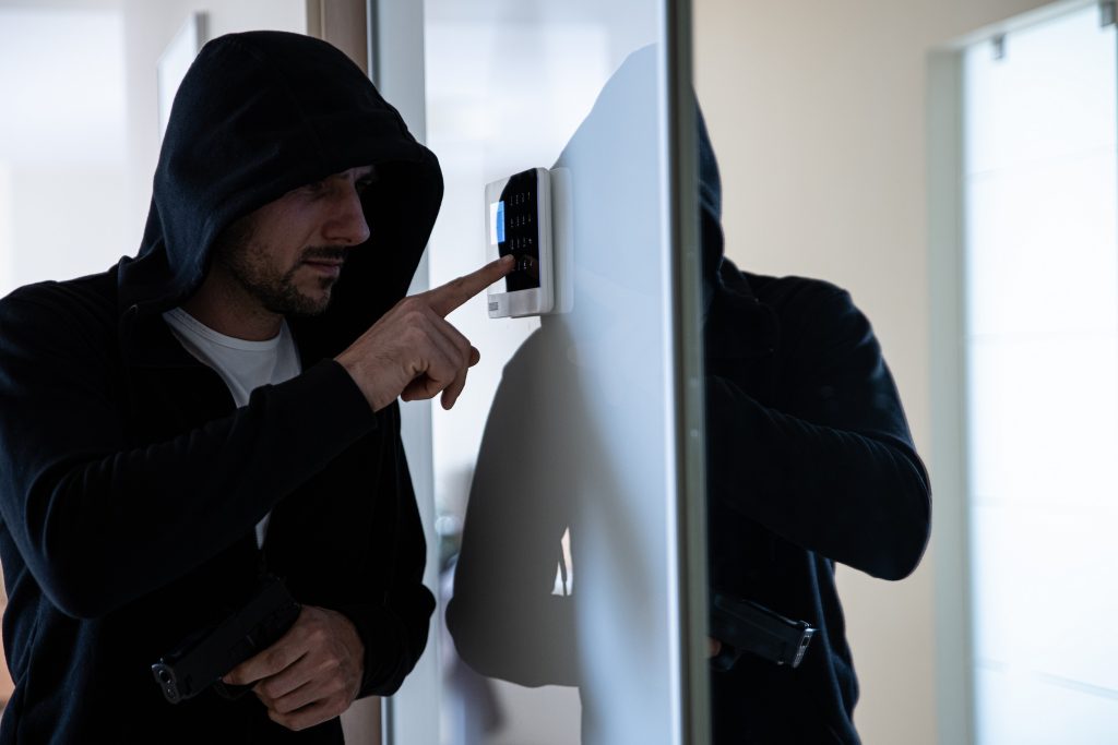 A burglar with a gun in his hand is trying to disarm the alarm. Break-in into the apartment.